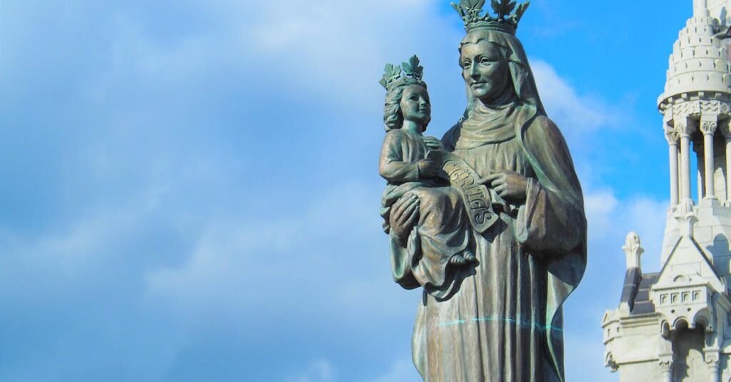 Bronze statue of Madonna and Child with crowns against a blue sky at Sainte-Anne-de-Beaupré Basilica.